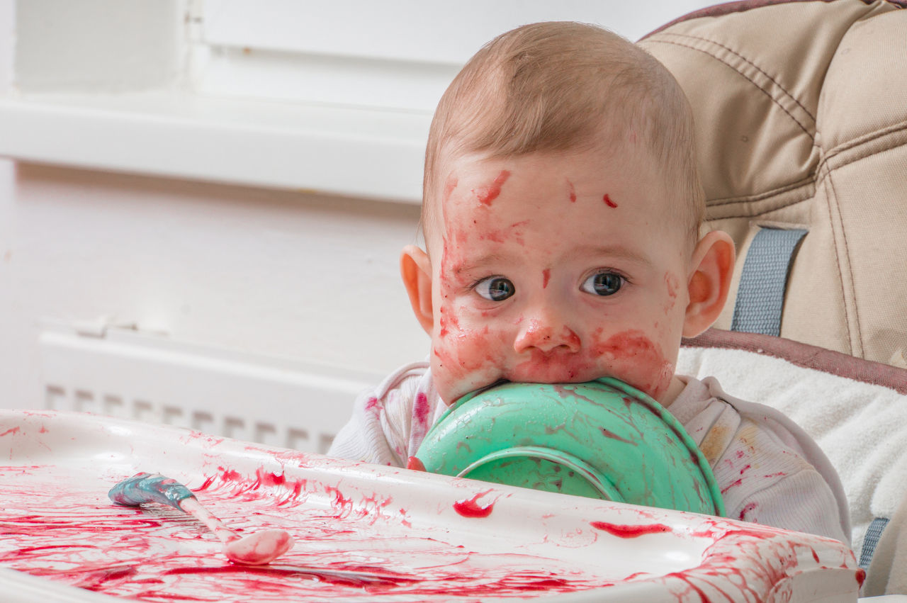 Bebe comendo sujo de papinha com o prato na boca