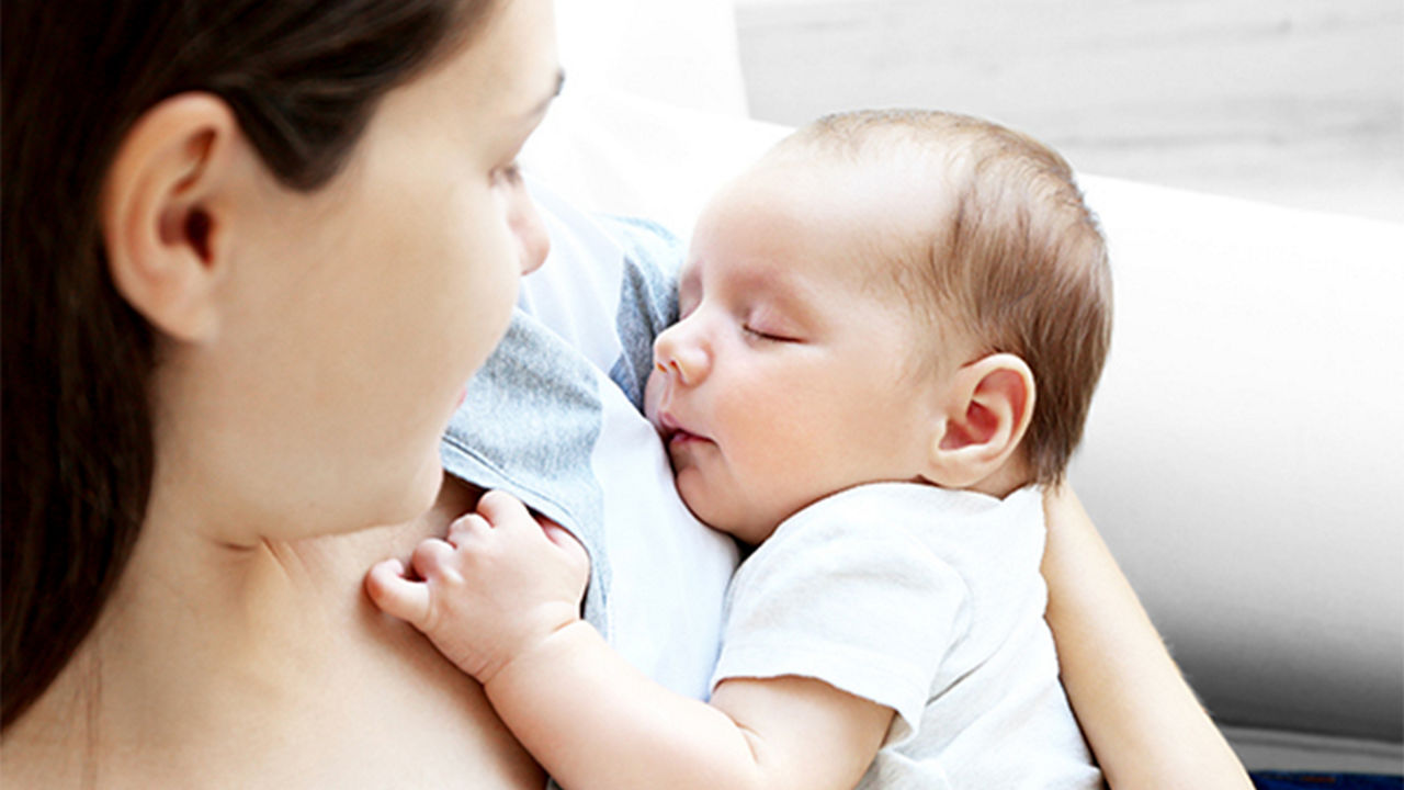 Bebé durmiendo en los brazos de la madre después de amamantar
