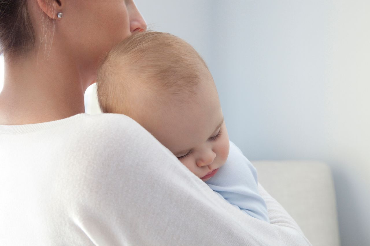 Close up of a mother with her eight months old baby boy sleeping in her arms. Photographed with a Canon 5D Mark II and developed from raw file.