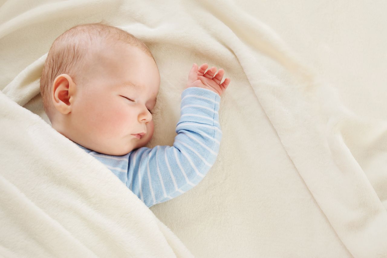 little boy sleeping on soft white blanket