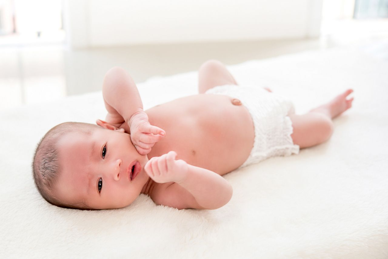 Adorable cute newborn shirtless baby wearing diaper lying on white soft wool sheet