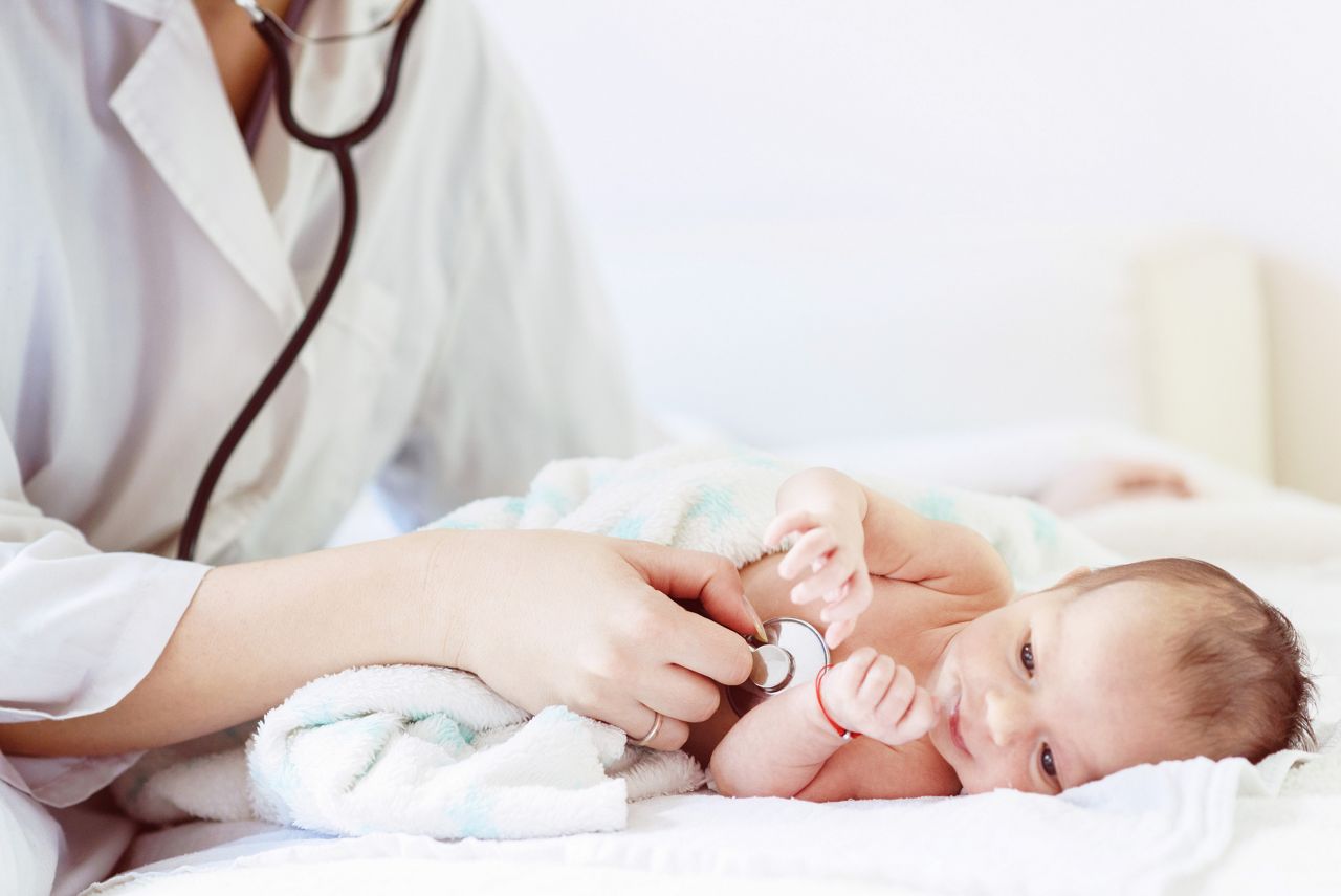 Pediatrician doctor examines newborn with stethoscope