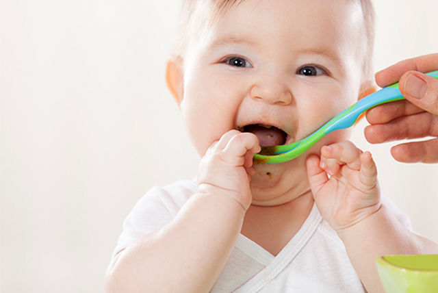 bebé sonriente comiendo con cuchara