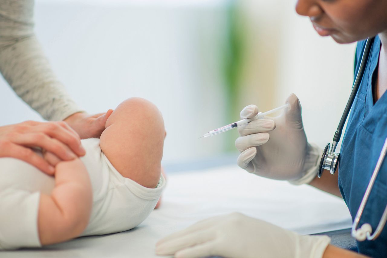 A baby is getting her vaccinations at the doctors office.