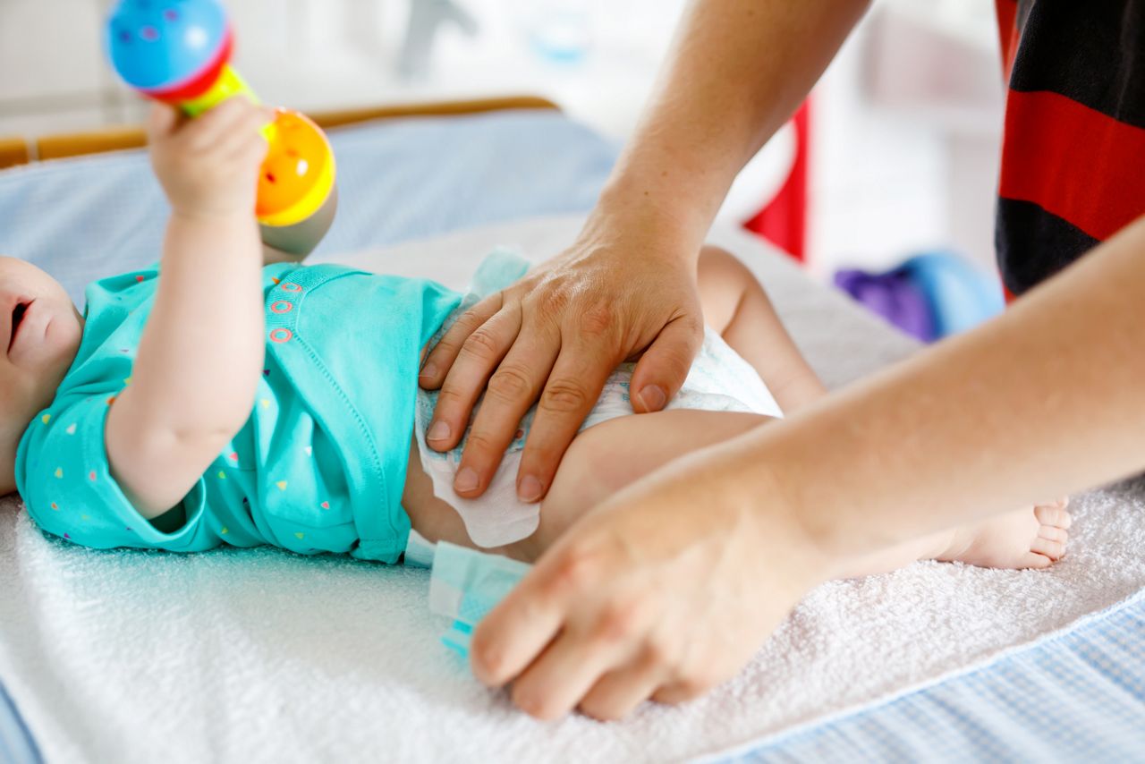 Cuidador trocando as faltas do bebe no trocador