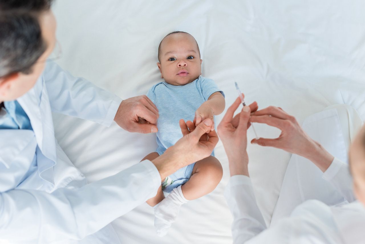 Medica aplica vacina na perna do bebe
