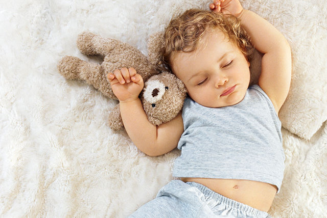 bebé vestido de azul durmiendo con osito de peluche