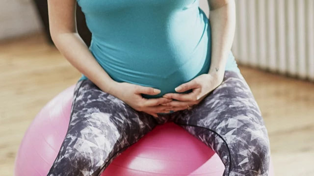 Pregnant mother sitting on a Yoga ball