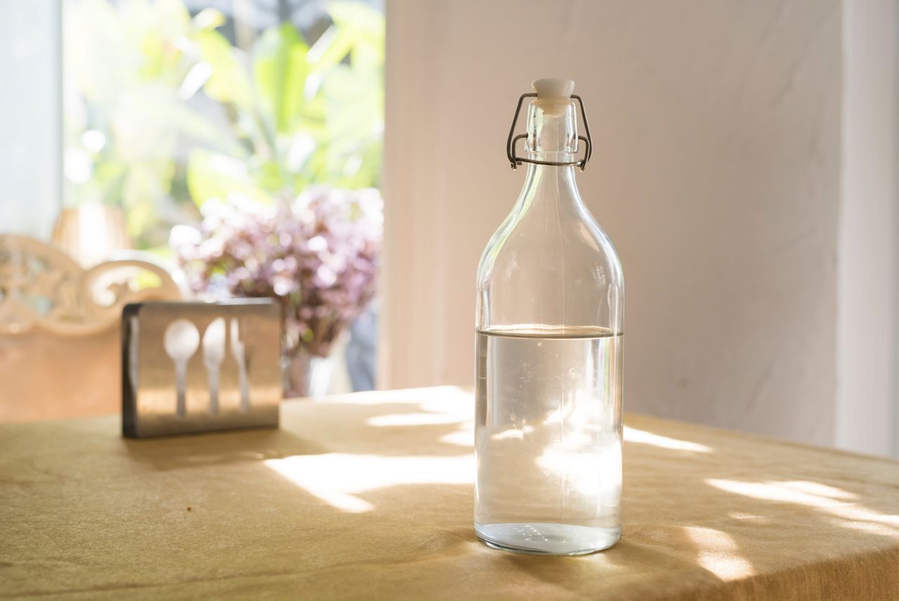 Close up Transparent Glass Bottle of Water on  Table with Napkin on the Metal Holder.