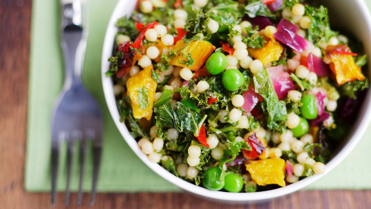 Un nutritivo tazón de ensalada de cuscús con verduras frescas y guisantes, ideal para una dieta saludable durante el embarazo