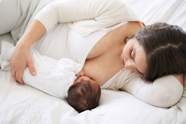 breastfeeding baby on bed