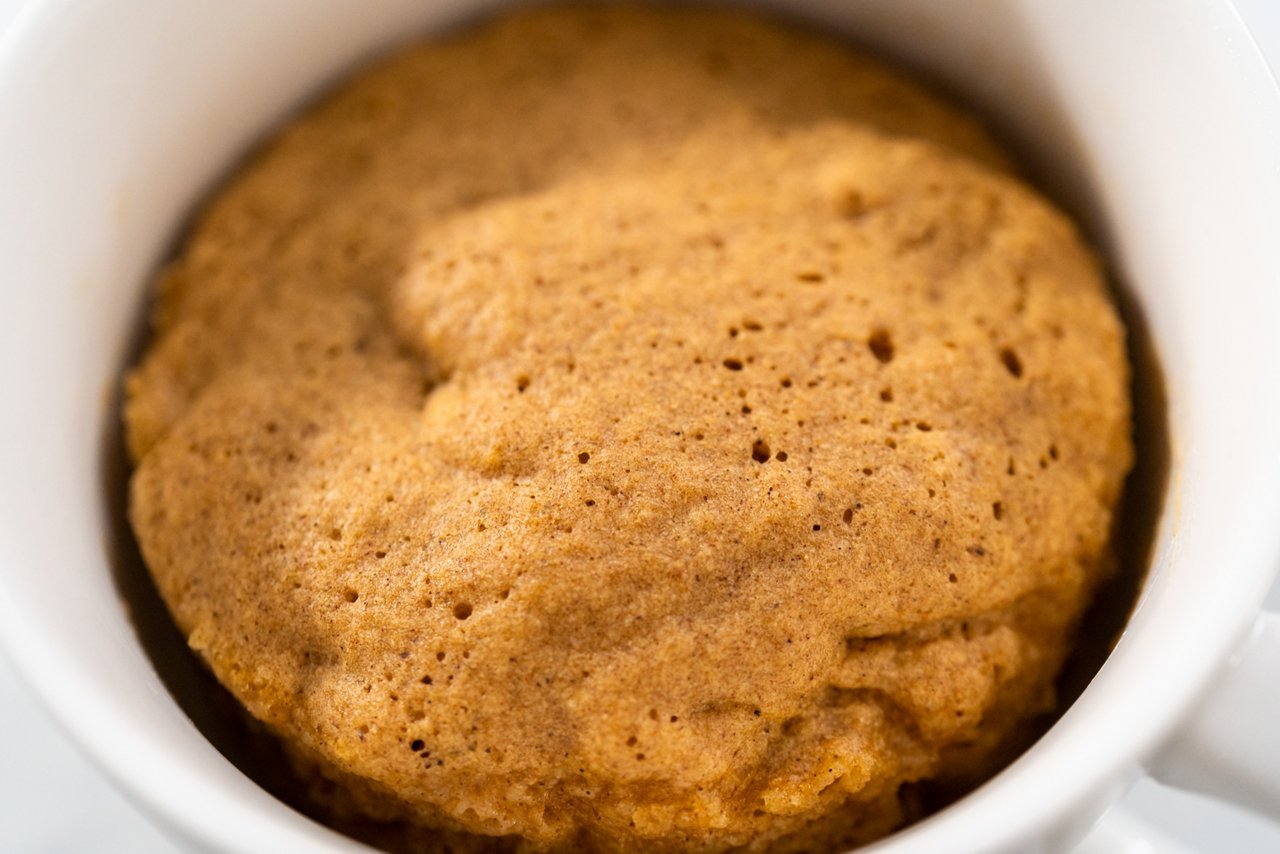 Freshly made to prepare pumpkin mug cake in a large white mug.