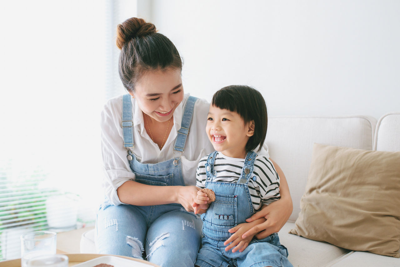 Cute little girl and her beautiful mother eating cookies.