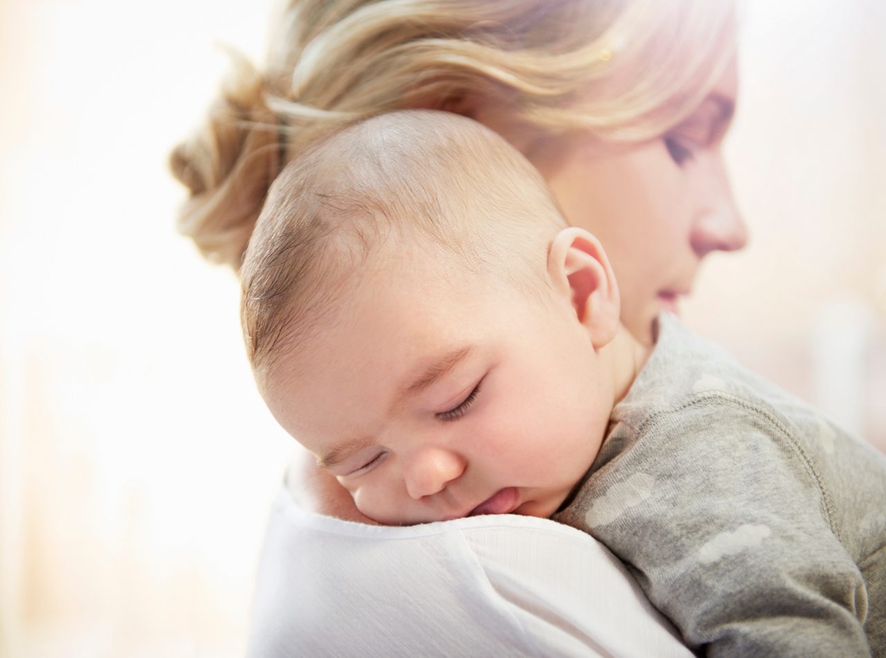 Baby schläft auf Arm der Mutter