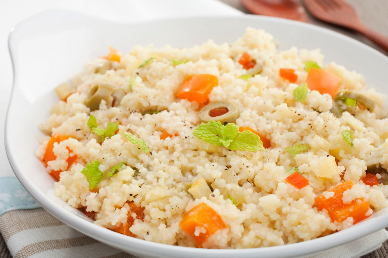 A bowl of couscous flavoured with stock and cheese, mixed with vegetables.