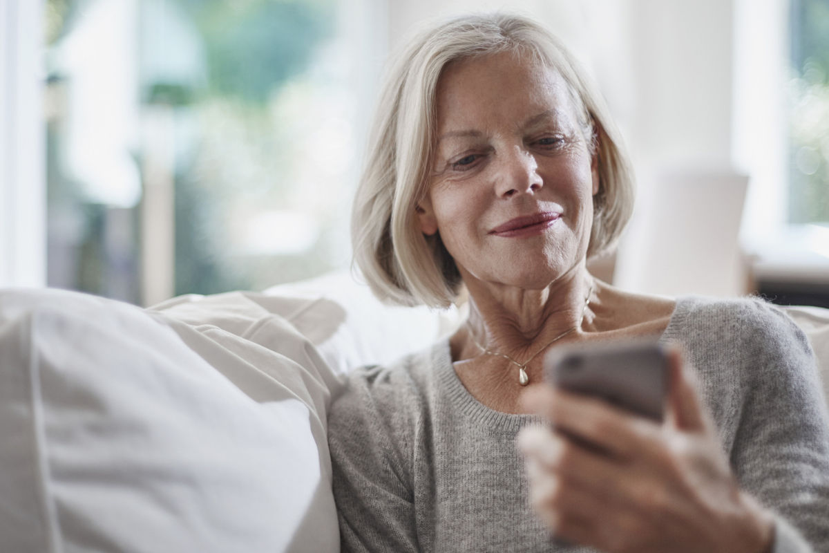 Senion woman sitting on a couch and looking at her phone