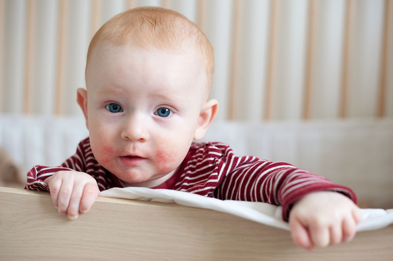 Baby standing in his crib looking at the camera