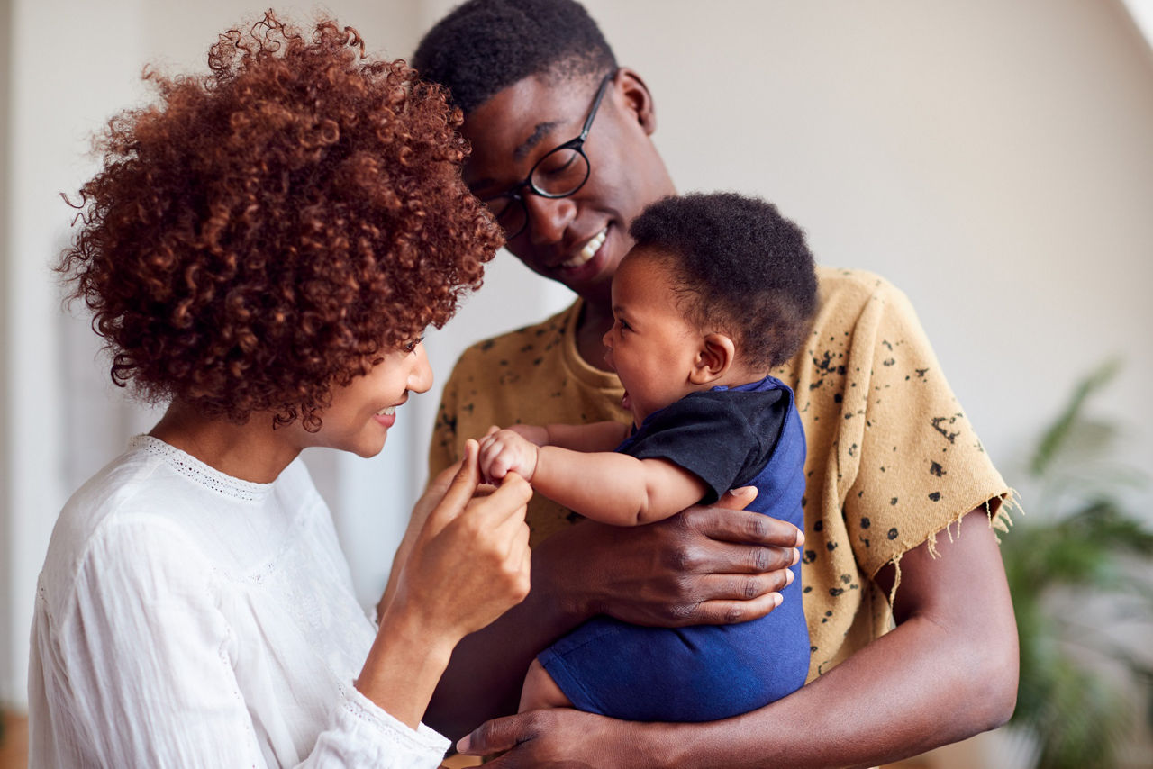 Parents holding a toddler in their arms and smiling