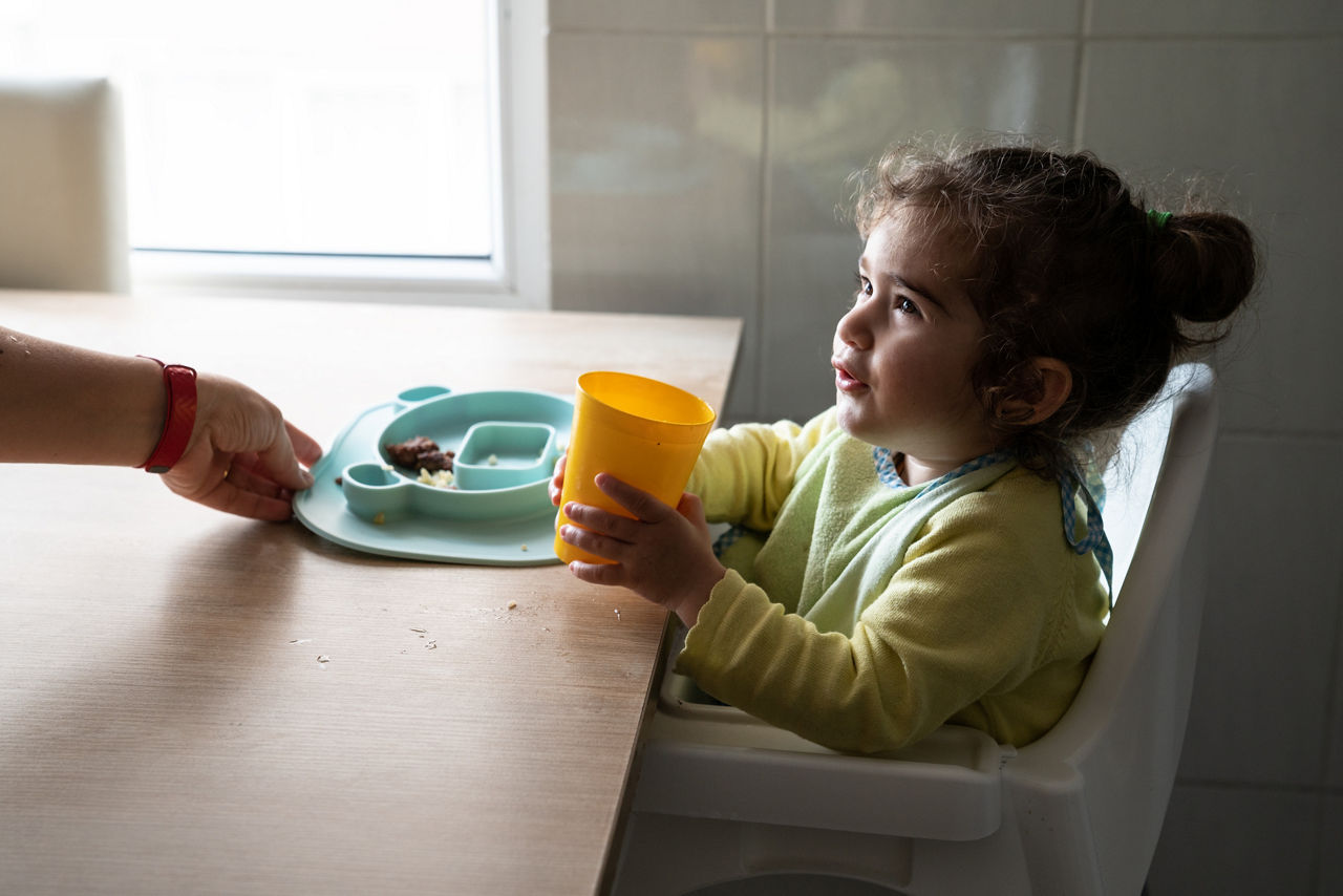 20 months baby girl sitting on high chair and eating food during Covid-19 pandemic lockdown. Shot indoor with a full frame mirrorless camera under natural daylight.