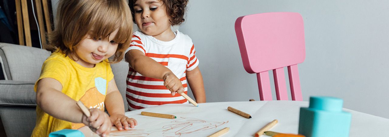From above of preschool kids playing with colorful blocks and drawing while spending time together in playroom of modern kindergarten. Children learning concept
