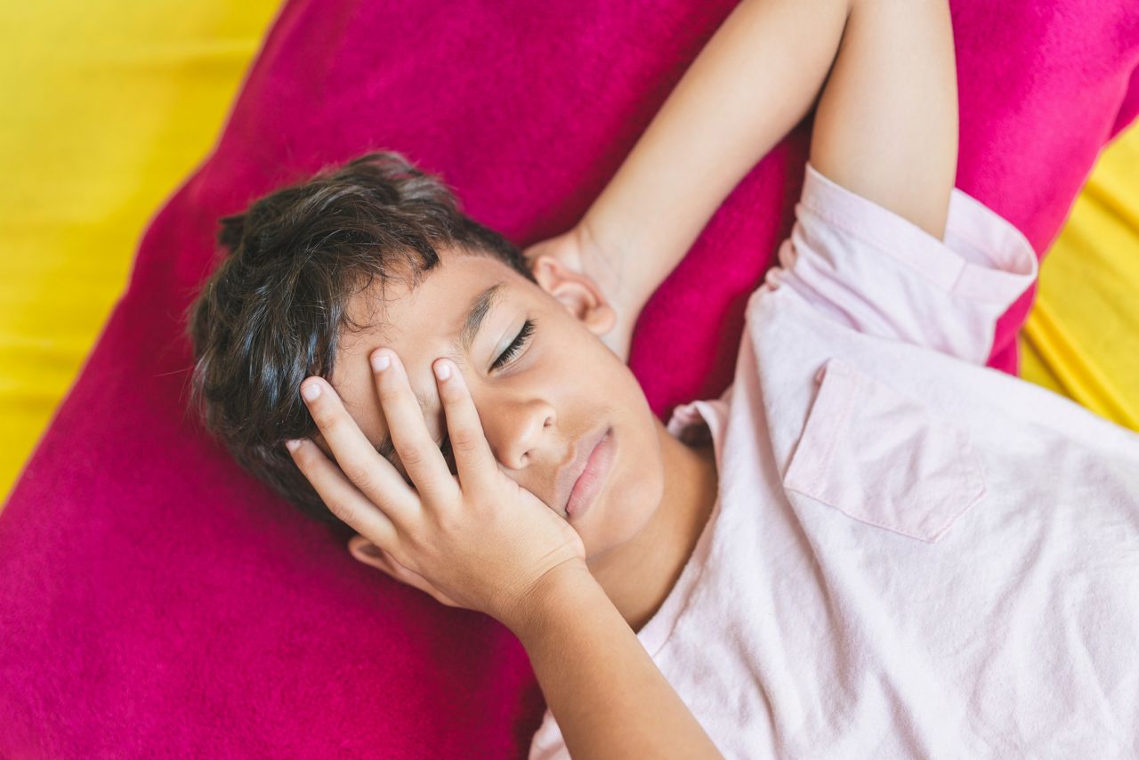 Boy with headache lying on the bed