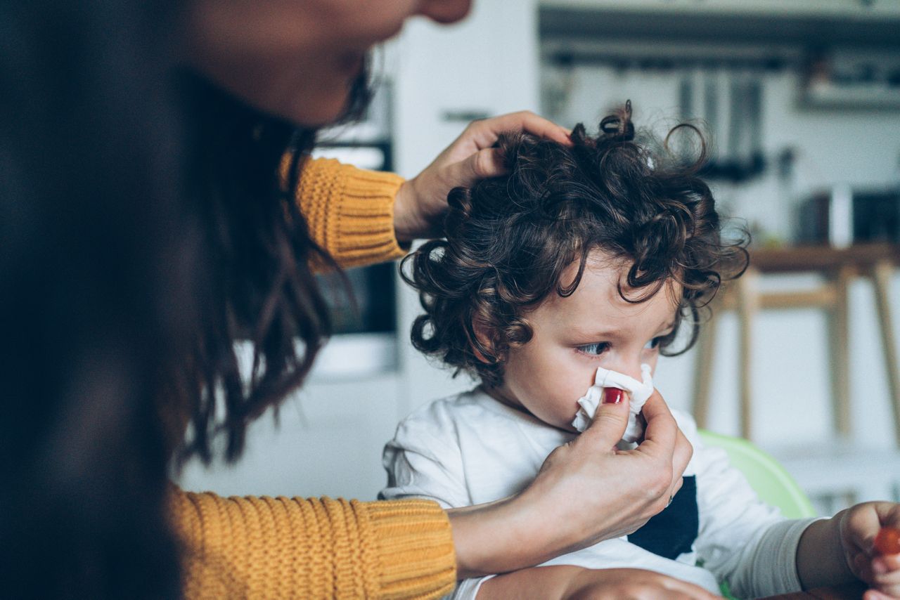 Mother helping son to blow his nose at home