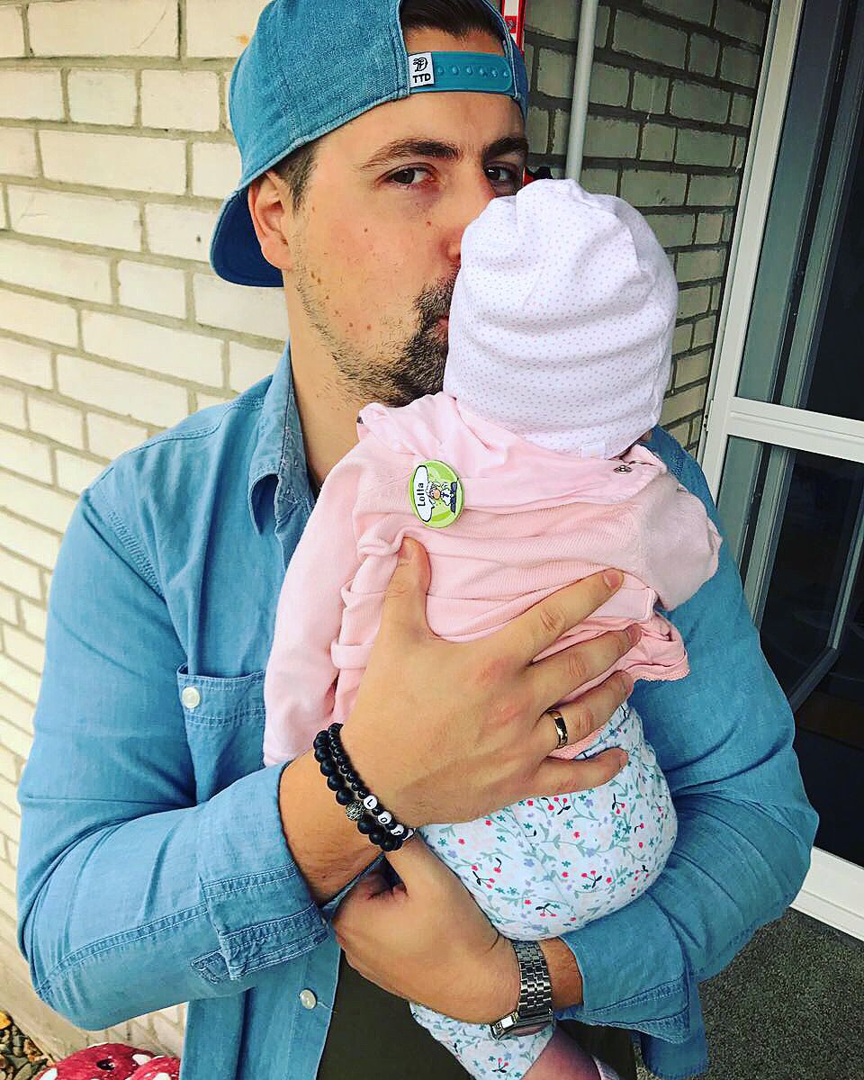 Vater hält und küsst Baby seitlich am Kopf
