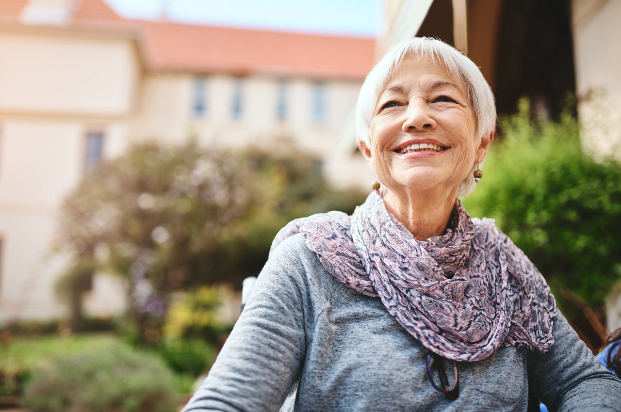 Frau mit Krebserkrankung schaut mit einem Lächeln nach oben