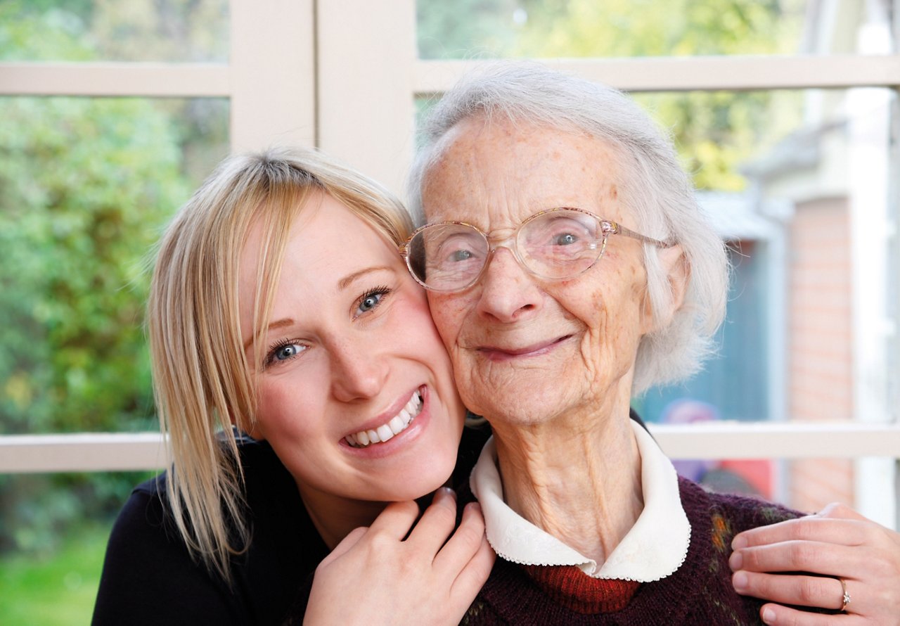 a young happy woman huggs an older happy elderly women