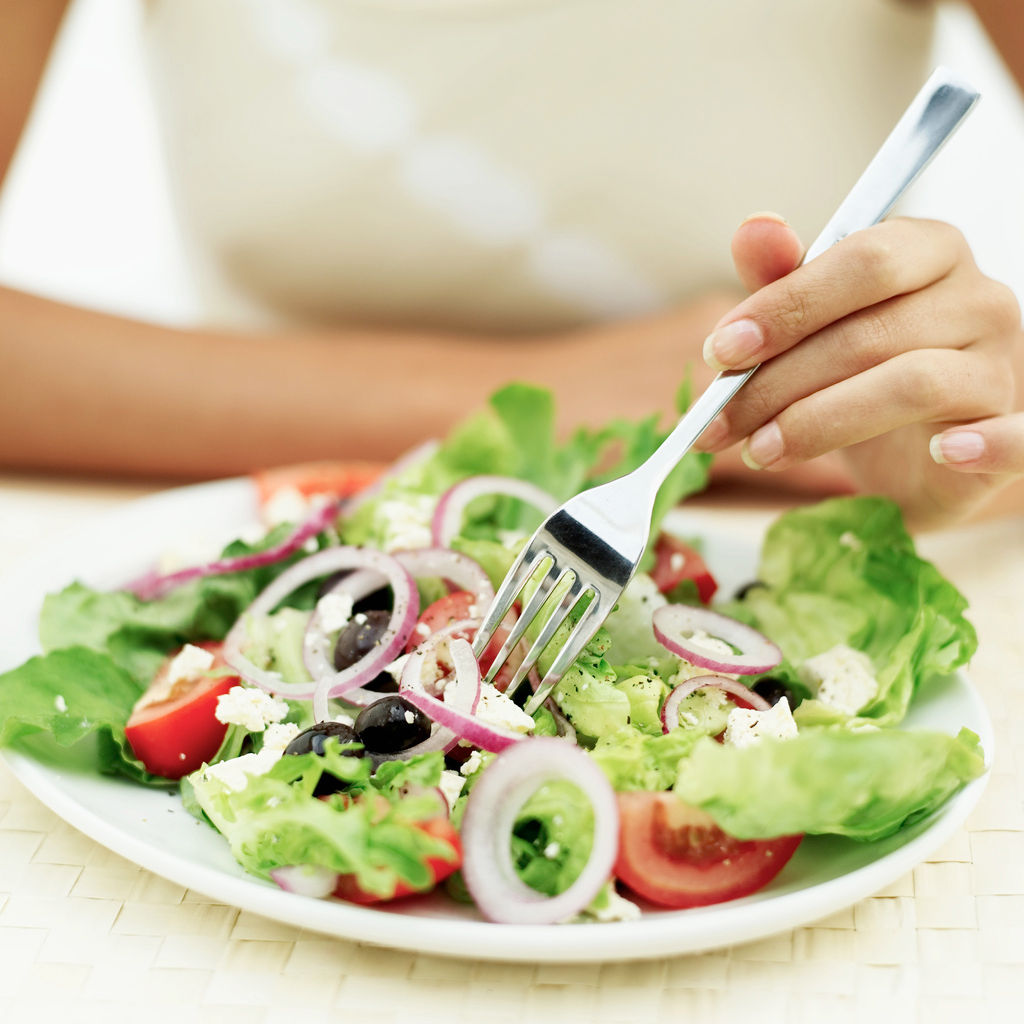 Close-up of a person eating salad with a fork