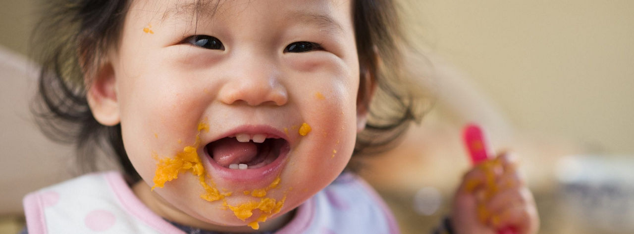 Enfant en bas �ge tenant une cuillere coloree a l'interieur