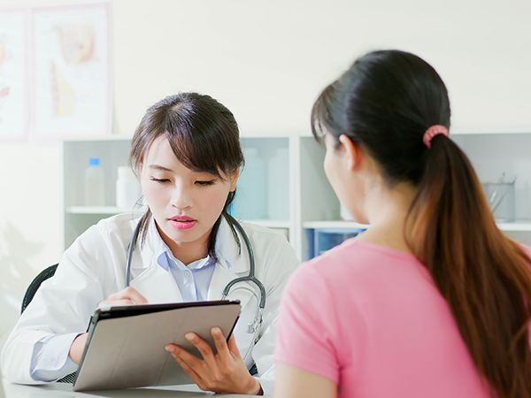 asian obstetrician diagnoses patient and use a digital tablet pc in the hospital