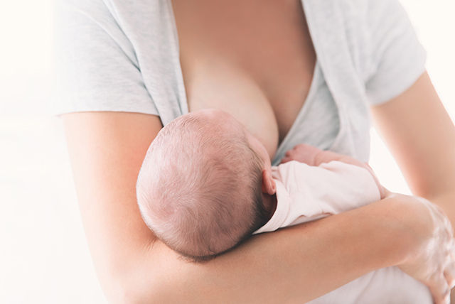 Bebé lactando de la madre con vestimenta clara