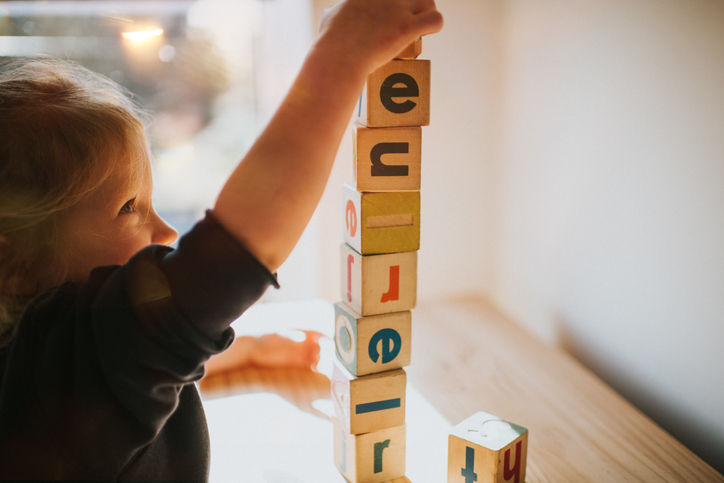 Cute little girl building letter blocks.