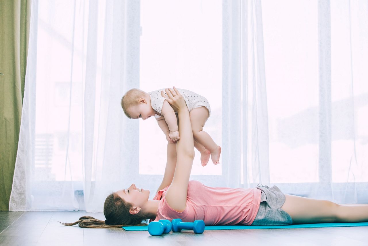 Mother and little toddler doing fitness at home on an exercise Mat together and smiling at home