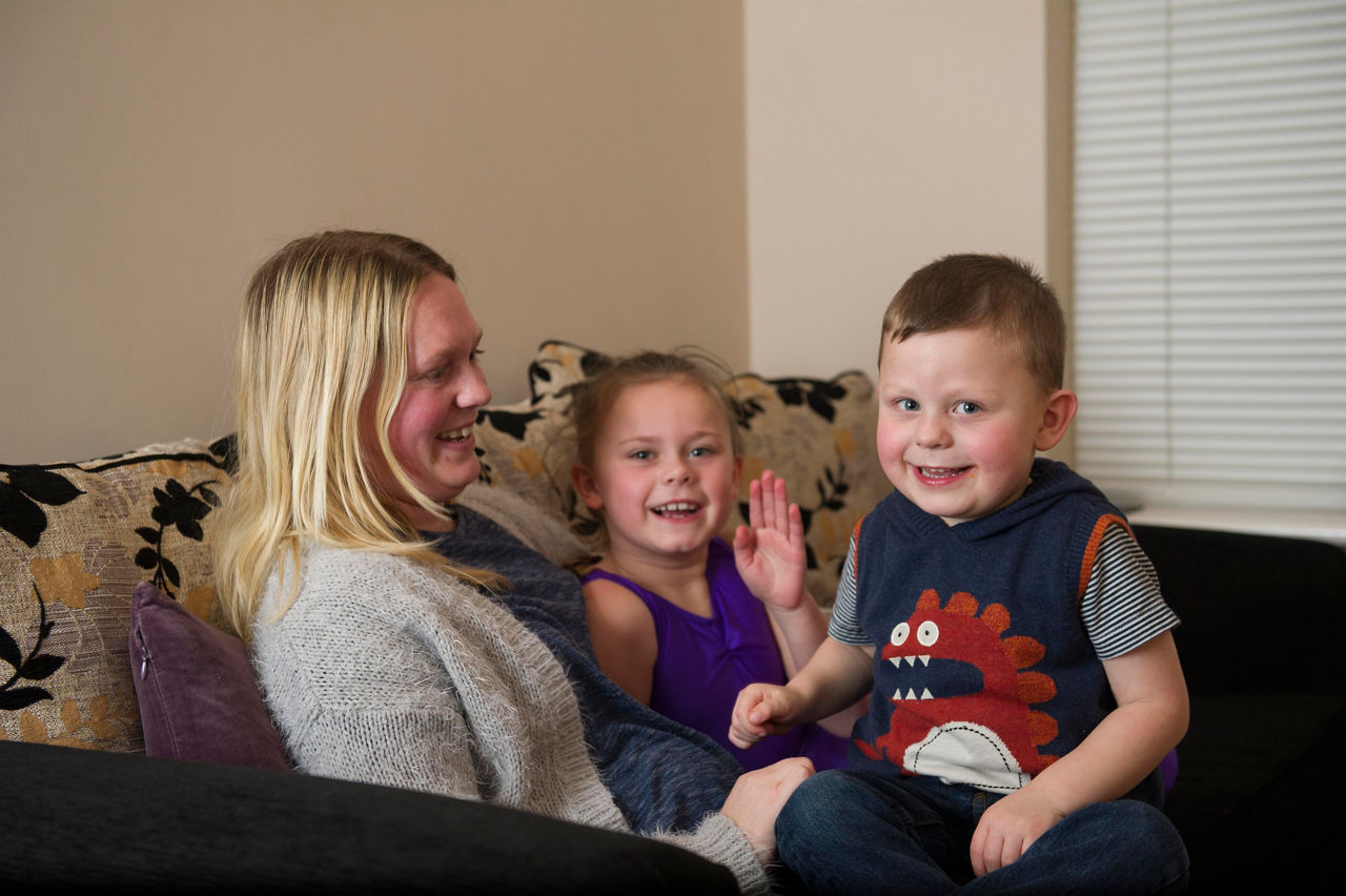 Mother with two children smiling and sitting on a couch