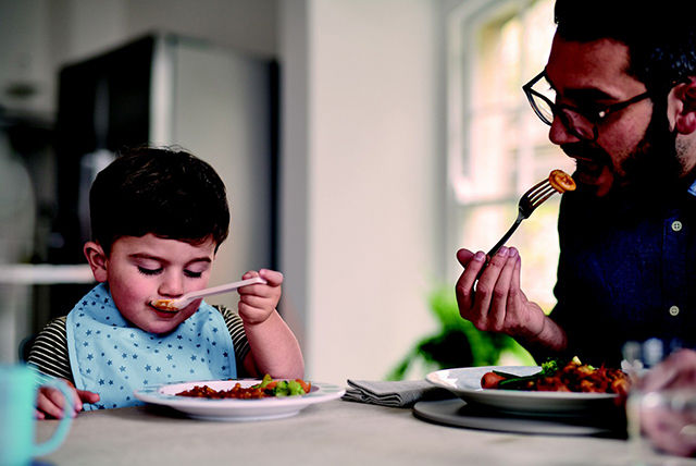 niño pequeño con papá comiendo juntos