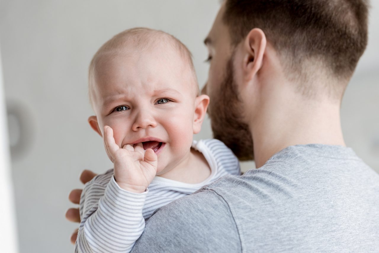 Baby in de armen van een ouder, als illustratie van troost, hechting en emotionele ontwikkeling in de vroege kindertijd