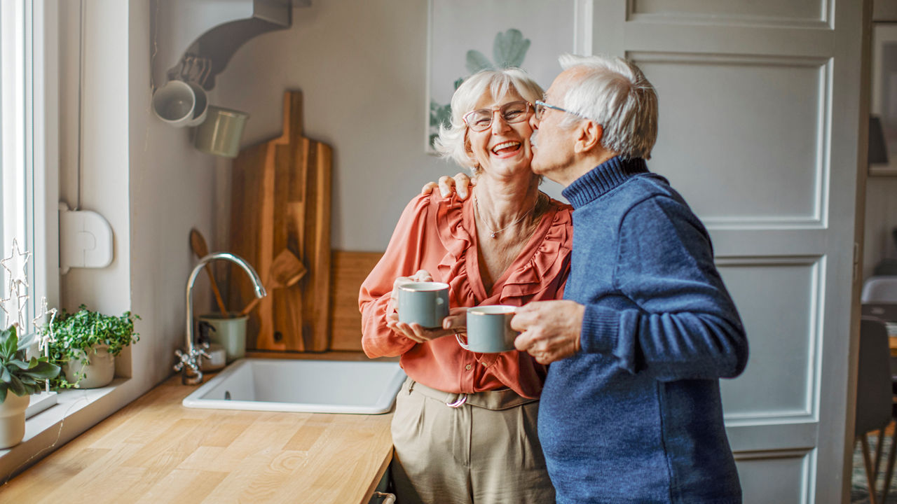Elderly couple kissing in kitchen