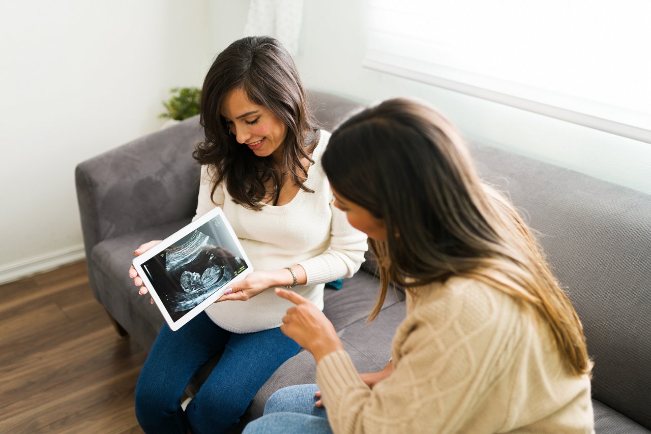 Latin doula speaking with a pregnant woman about the ultrasound of her baby. Expectant mother and midwife discussing the health of the baby at home getty images 1304285635