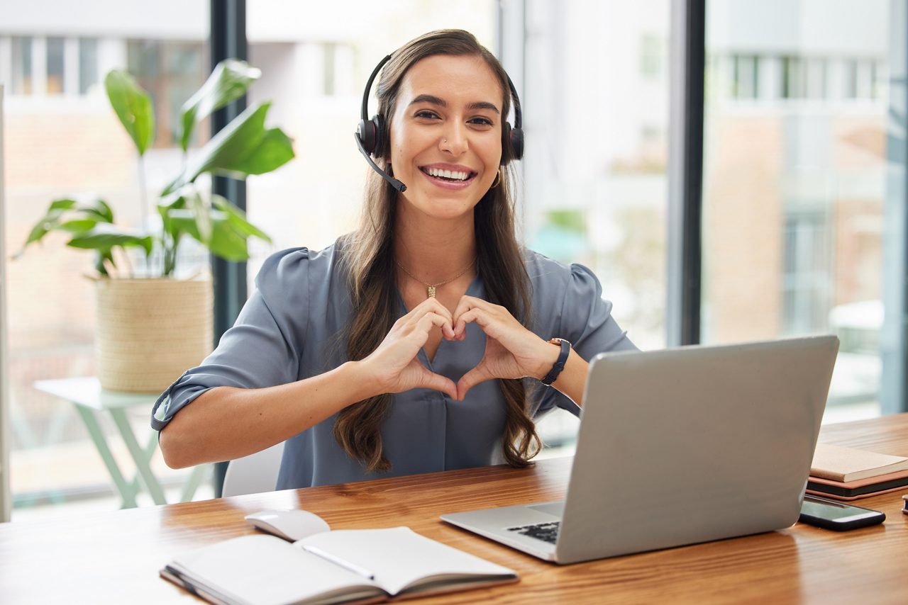 Woman, call center and laptop with heart gesture for telemarketing, customer service or support at the office. Portrait of happy employee consultant with smile and hands with love symbol by computer getty images 1465951198