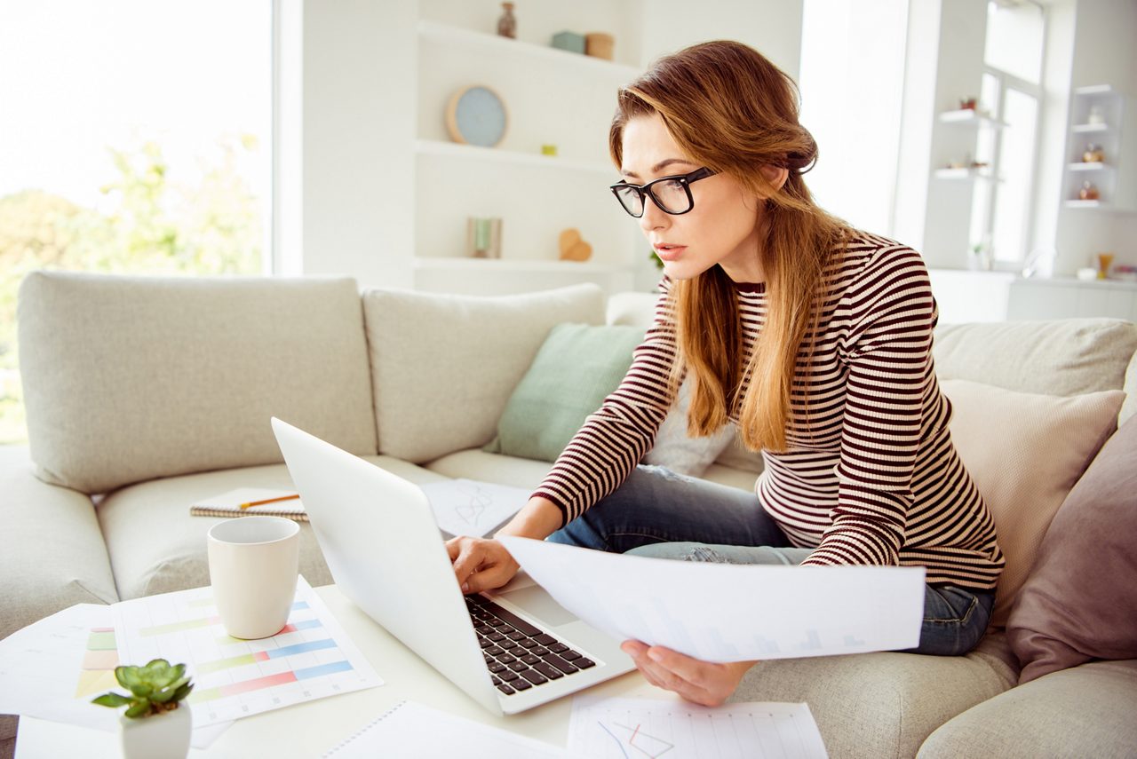 Close up photo beautiful she her model lady hands arms hold paper student test attentive search notebook wear jeans denim striped pullover clothes sit comfort cosy divan house living room indoors.getty images 1147284621