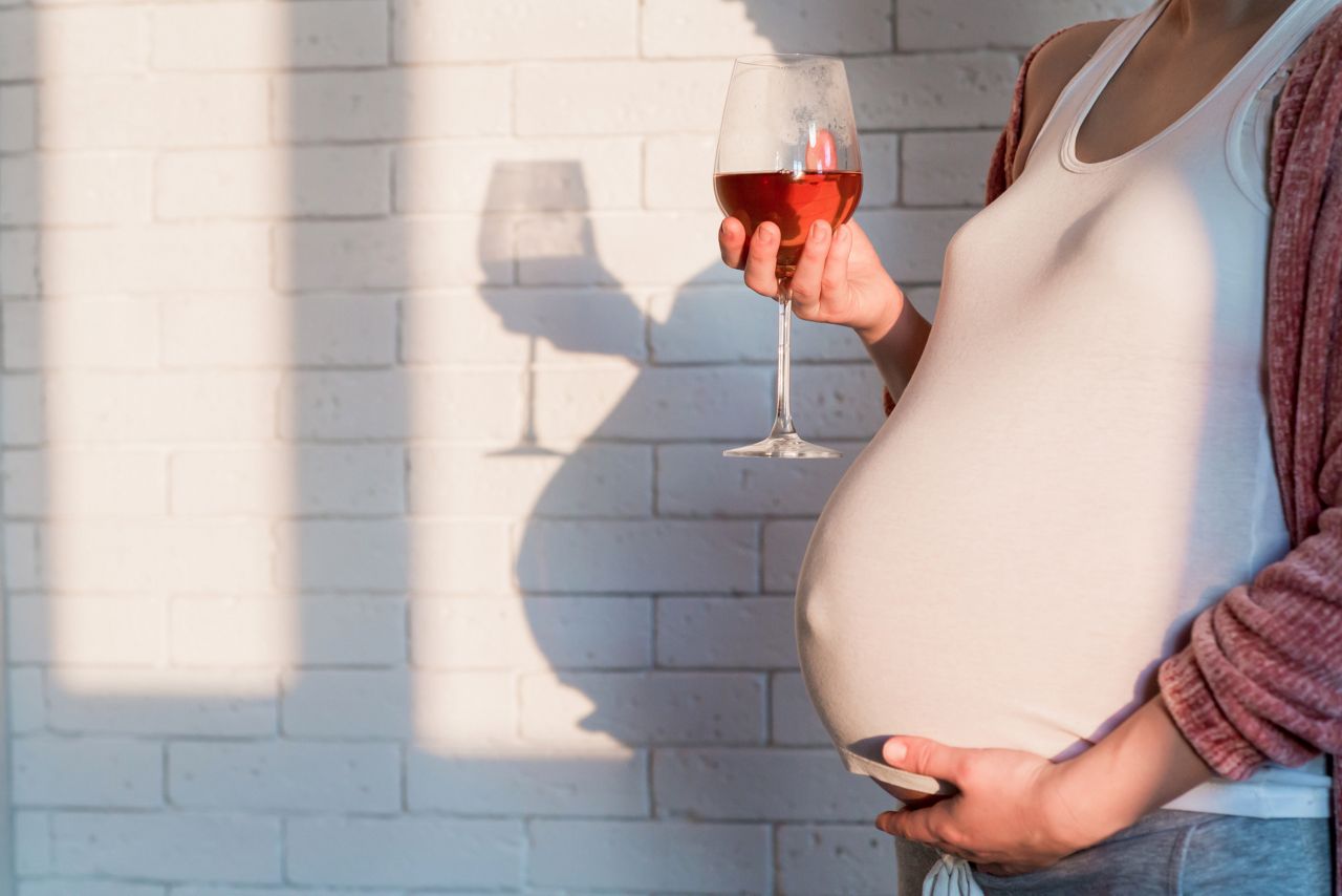 Unrecognized Pregnant woman with glass of red wine in hand