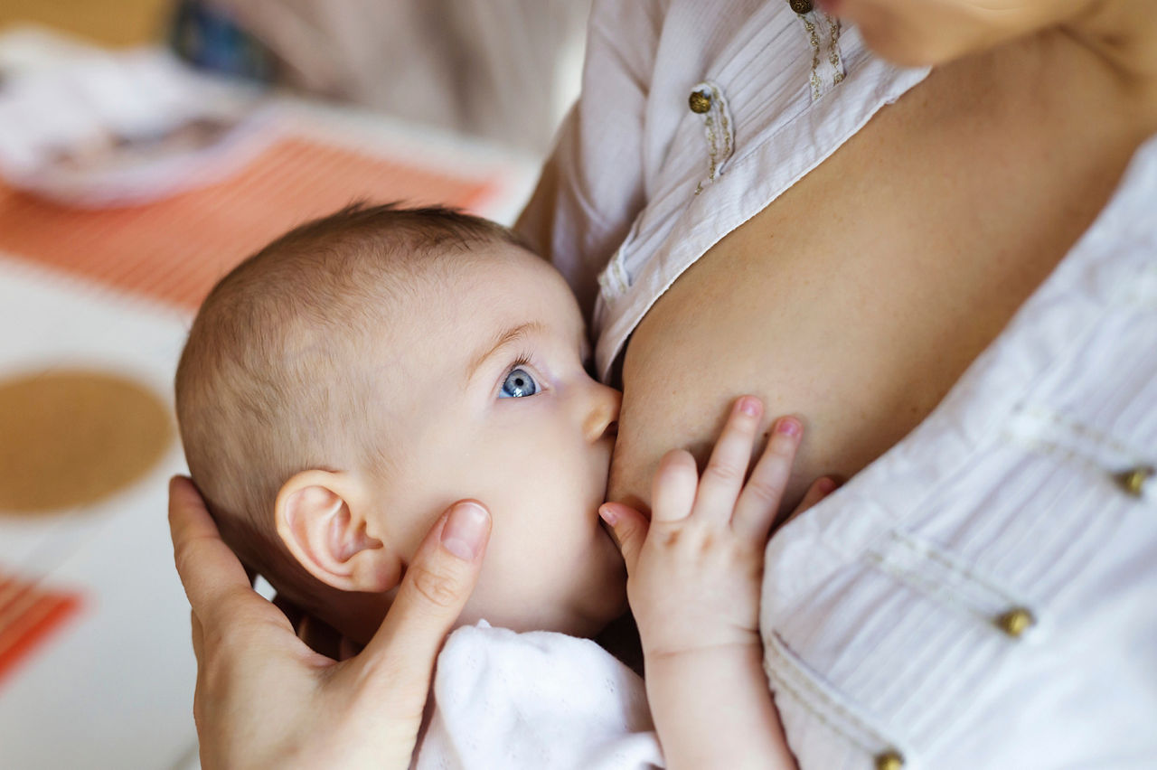 Mother breastfeeding her little baby girl in her arms.