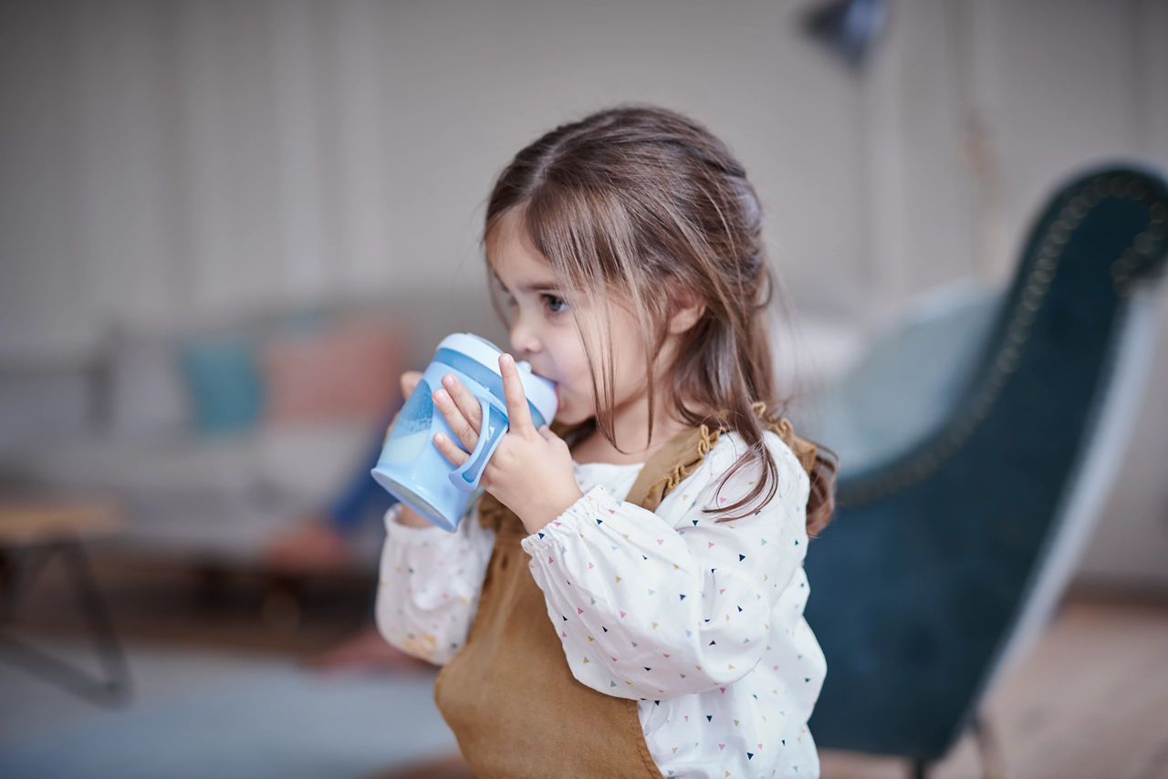 Girl drinking from feeding beaker