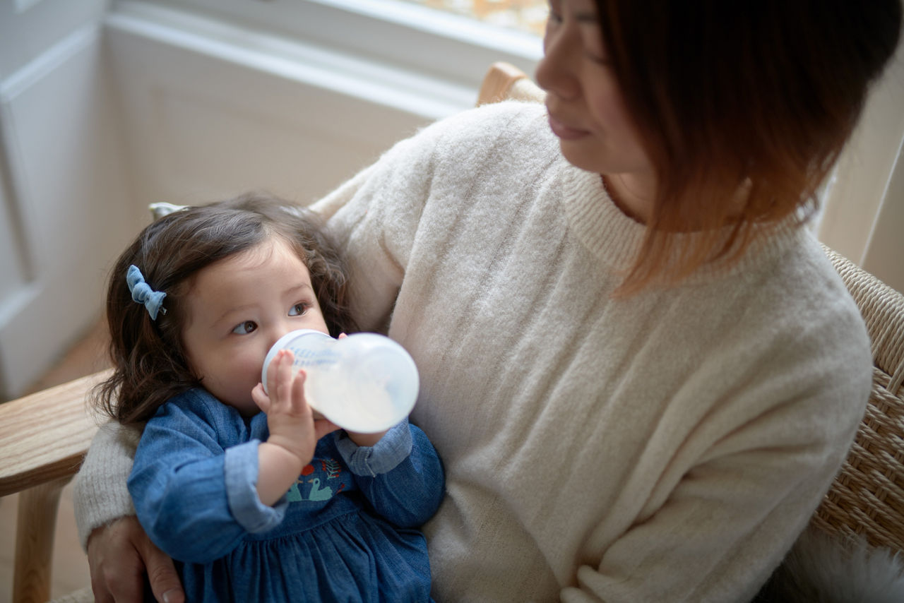 Girl drinking milk in mother's arms