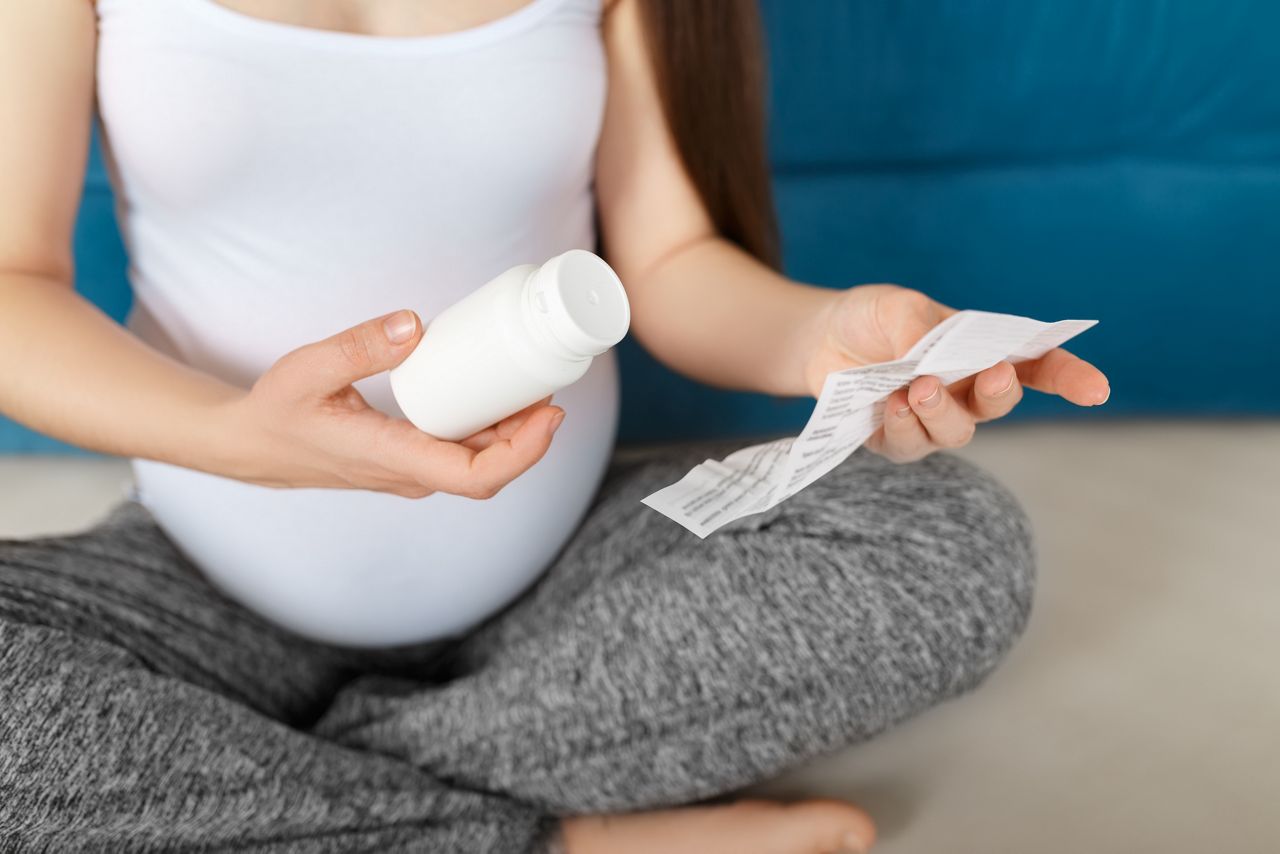 closeup pregnant belly. Pregnant woman holding bottle of pills and prescription. Expectant mother reading leaflet before take a tablets. Third trimester. Pregnancy, healthcare, treatment concept