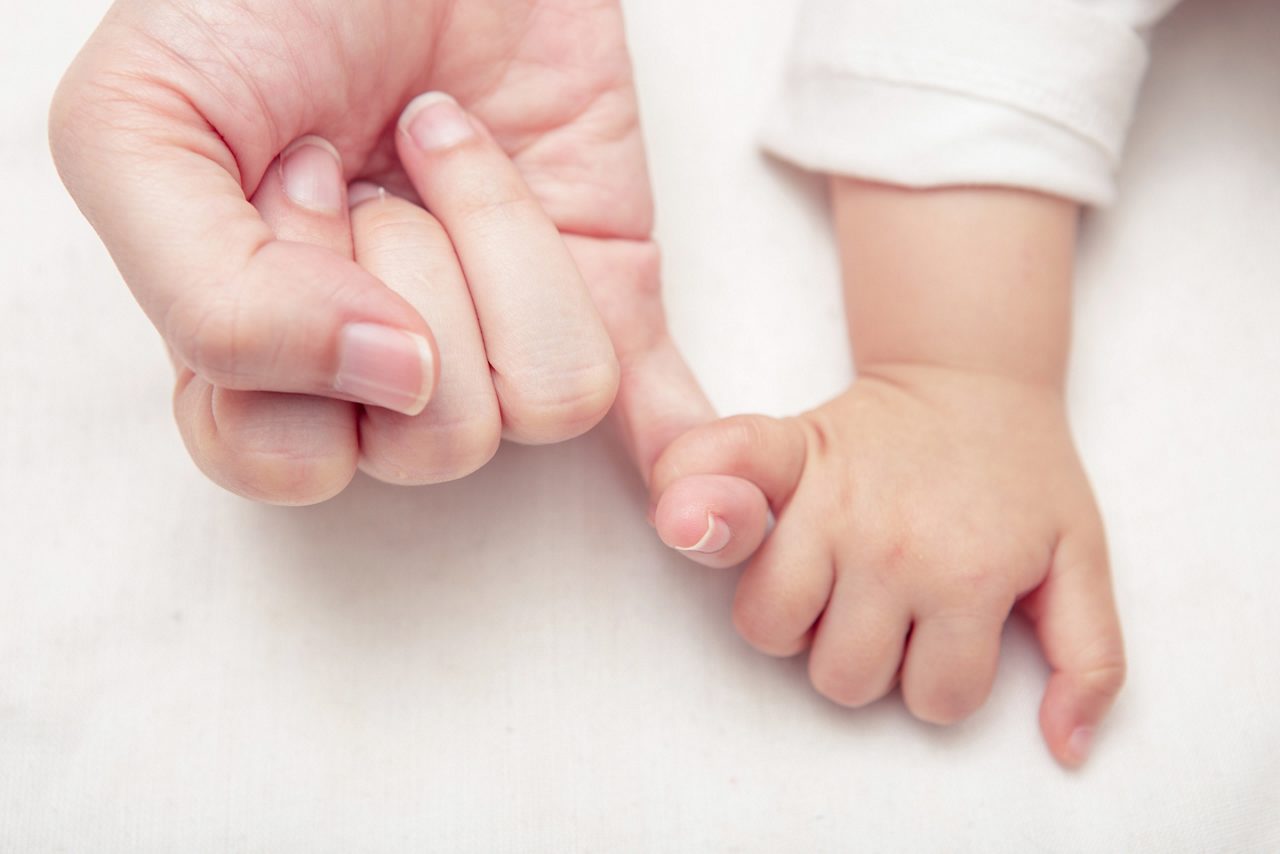 Babyhand hält Hand von Mama oder Papa