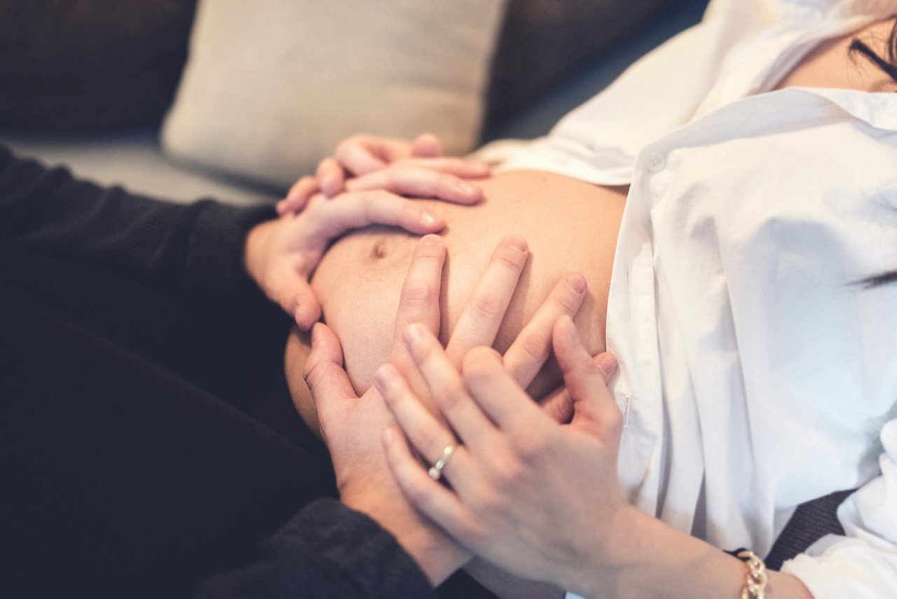 Happy future father holding hands and touching belly of pregnant wife maternity concept