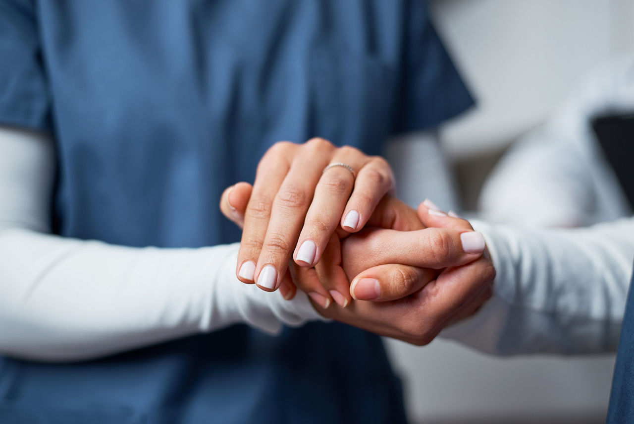 A professional nurse provides emotional support by gently holding a patient's hand, symbolizing care and empathy. This closeup image communicates trust, kindness, and the human connection within the medical field.